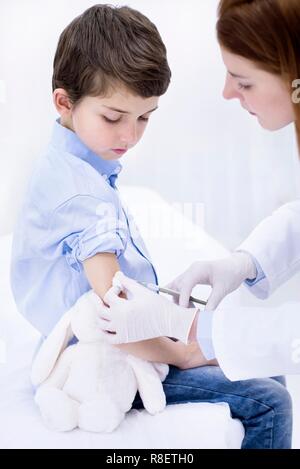 Doctor giving boy injection in arm. Stock Photo