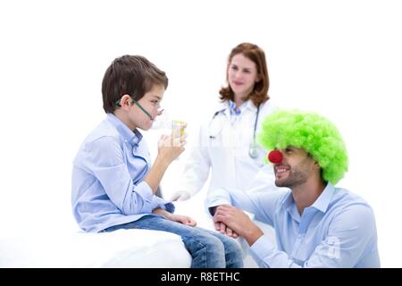 Boy using nebuliser with doctor dressed as clown. Stock Photo