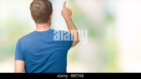Handsome middle age hoary senior man wearin glasses over isolated background Posing backwards pointing behind with finger hand Stock Photo