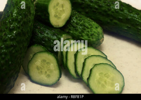 Green wet cucumbers with cut on yellow textured table Stock Photo