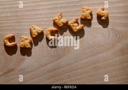 Happy birthday. Text from the salty crackers as printed English letters  that lie on a wooden chopping board. Message, lined with edible letters  Stock Photo - Alamy