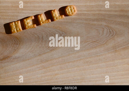 Hello. Text from the salty crackers as printed English letters that lie on a wooden chopping board. Message, lined with edible letters Stock Photo
