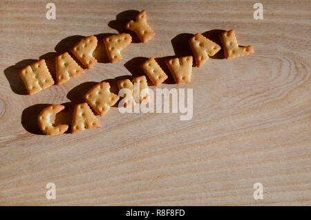 Happy birthday. Text from the salty crackers as printed English letters  that lie on a wooden chopping board. Message, lined with edible letters  Stock Photo - Alamy