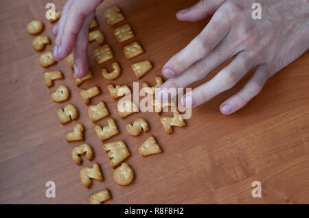Men's fingers typing on the keyboard, which is composed of salty cracker in the form of letters and numbers. Simulating a computer keyboard using of c Stock Photo