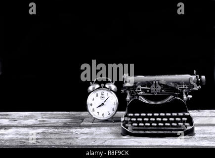 Antique portable typewritter and alarm clock made in 1917 with room for your type in black and white. Stock Photo
