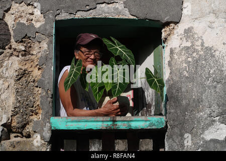 An Ivatan woman peeps out from a window in Savidug Barrio located in Sabtang the southernmost island of the Batanes island group the northernmost archipelago province of the Philippines situated in the Cagayan Valley region Stock Photo