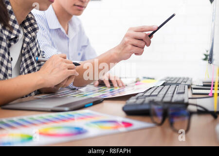 Creative or Interior designers teamwork with pantone swatch and building plans on office desk, architects choosing color samples for design project Stock Photo