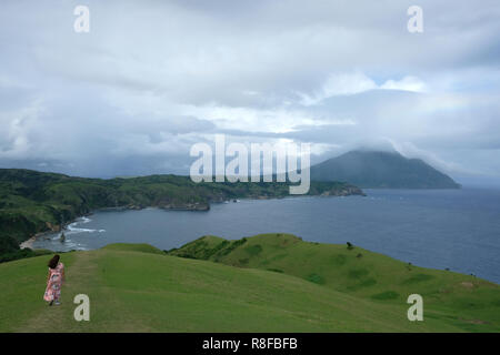 A woman walks in the vast pastureland of Rakuh A Payaman commonly known as Marlboro Hills or Marlboro Country in Batan the main island of Batanes the northernmost archipelago province of the Philippines situated in the Cagayan Valley region Stock Photo