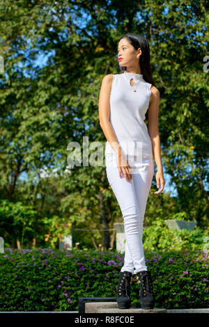 Beautiful woman posing - standing, cross legged and looking away Stock Photo