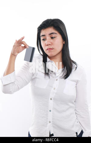 Photo image portrait of a sad Asian woman while looking to her credit card, economic depression, bankruptcy concept, close up portrait over white Stock Photo