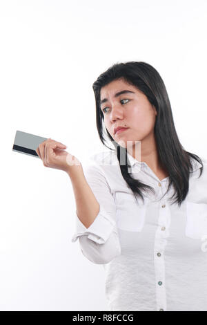 Photo image portrait of a sad Asian woman while looking to her credit card, economic depression, bankruptcy concept, close up portrait over white Stock Photo