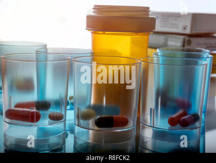 Several plastic glasses with daily medication in hospital, conceptual image Stock Photo