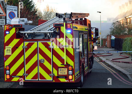 Emergency services respond to a house fire in a residential street in East London with a number of Fire Engines including an Aerial Platform Stock Photo