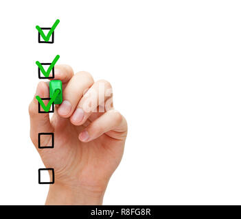 Hand putting three check marks with green marker on blank customer survey checklist on transparent glass board. Stock Photo