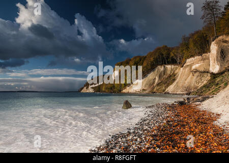 Chalk cliffs on the island of Rügen in the National Park Jasmund. The sun illuminates the chalk cliffs. The sea turns white and turquoise colored. Stock Photo