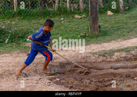 Thakhek, Laos - April 20, 2018: Boy working in the mud in a remote rural zone of Laos. Child employment in Laos is very common Stock Photo