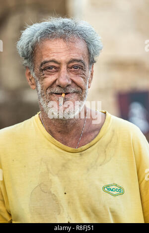Rhodes, Greece - October 10th, 2018: Portrait of a greek mature man smoking with grey hair and beard, looking at camera happy, who works at the port o Stock Photo