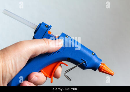 Close up of a hand holding a hot glue gun Stock Photo