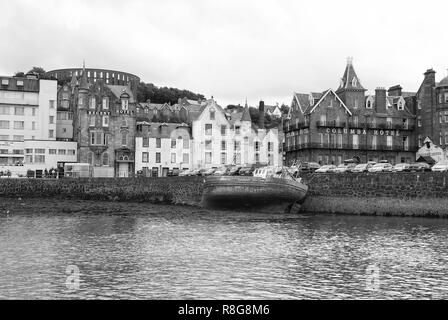 Oban, United Kingdom - February 20, 2010: bay with houses on grey sky. City architecture along sea quay. Resort town with hotels. Summer vacation on island. Travelling and wanderlust. Stock Photo