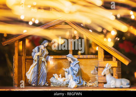 Christmas Manger scene with figurines including Jesus, Mary, Joseph and sheep. Focus on mother! Lights trail in front of camera. Stock Photo