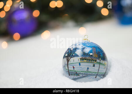 Christmas ornaments in snow with sparkling lights in the background Stock Photo