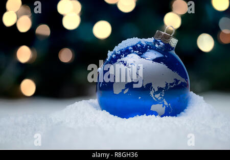 Christmas ornaments in snow with sparkling lights in the background Stock Photo