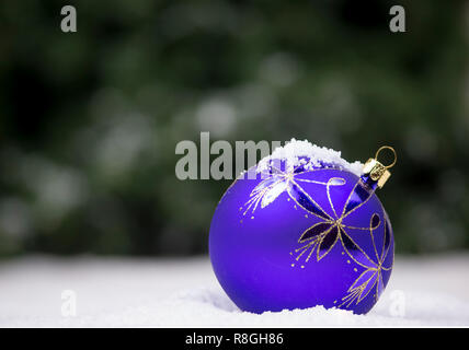 Christmas ornaments in snow with sparkling lights in the background Stock Photo