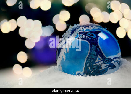 Christmas ornaments in snow with sparkling lights in the background Stock Photo