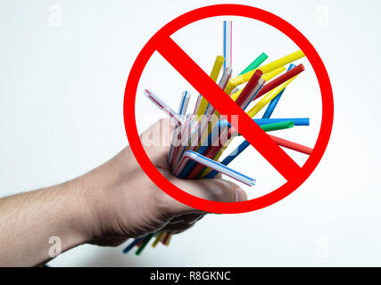 handful of plastic drinking straws which banned in California state in hand with red prohibited sign cross out Stock Photo