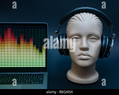 electronic music concert flyer banner concept with laptop, dummy head with headphones, and equalizer on display. low key image Stock Photo