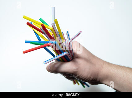 hand holding a bunch of vibrant drinking straws on white background Stock Photo