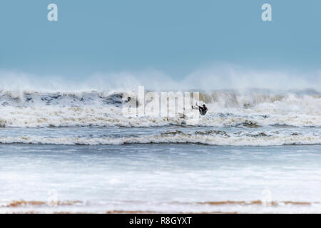 A surfer loses control as he is dwarfed by the waves on a winters day at Westward Ho! beach in North Devon. Stock Photo