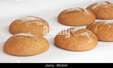 Several round fresh hot breads on the white tablecloth or shelf in the bakery Stock Photo