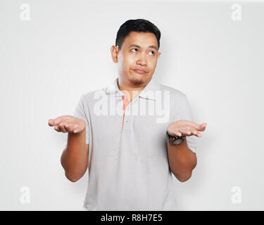 Photo image portrait of a cute handsome young Asian man showing unhappy face, looking to the side with both of his palm open Stock Photo