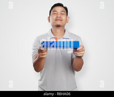 Photo image portrait of a cute handsome young Asian man smiling while giving blue gift box package Stock Photo