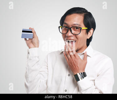 Photo image portrait of a funny young Asian businessman looked happy and smiling while showing a credit card that he hold, close up portrait, commerce Stock Photo