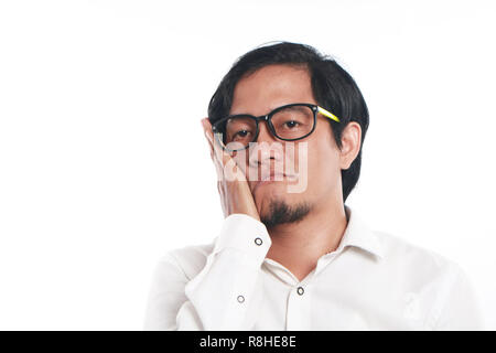 Photo image portrait of a funny young Asian businessman wearing glasses looked very bored or having toothache, close up portrait showing sad face with Stock Photo