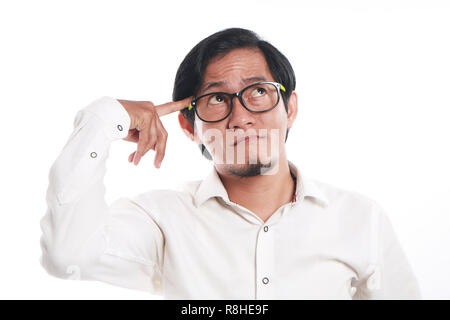 Photo image portrait of a funny young Asian businessman wearing glasses seriously thinking of something, close up portrait with pointing finger touchi Stock Photo