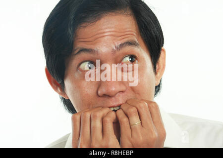 Photo image portrait of a funny young Asian businessman looked very scared and worried, close up portrait, biting nails gesture over white background Stock Photo