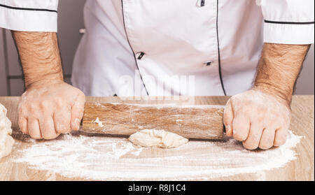 male cook kneads dough on the table, hands close-up Stock Photo