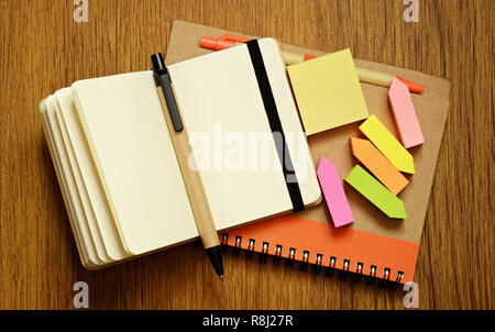 Notebooks, pens and stickers on wooden background Stock Photo