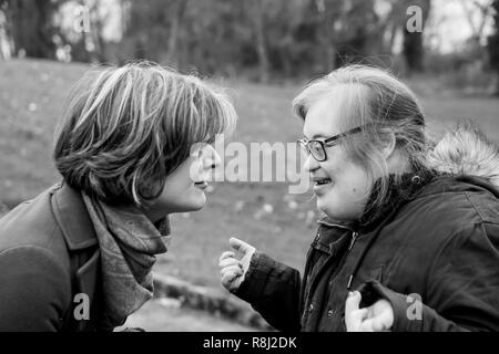 Hakendover, Flanders / Belgium - 11 20 2017: Young caucasian woman with Down Syndrome smiling and talking to a white woman Stock Photo