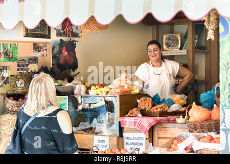 Croatia, Split - September 22th, 2018: A female seller speaking with happiness with a customer at her grocery store in a public market in Split, Croat Stock Photo