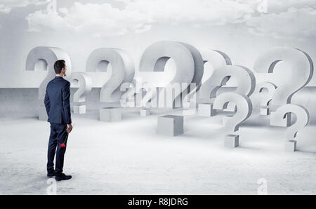 Businessman standing and looking to a bunch of question mark signs  Stock Photo