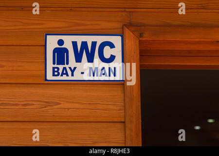 Direction sign to the toilet on the background of a wooden wall. Daylight. Close-up Stock Photo