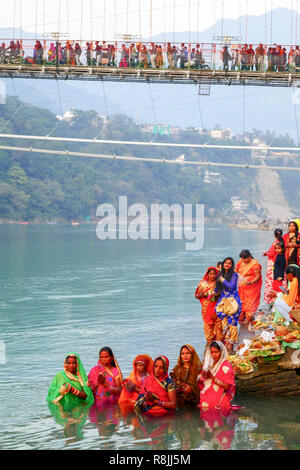 group of women in colourful saris praying in the water of river Ganga at Rishikesh, India Stock Photo