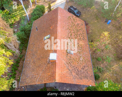 Inspection of the red tiled roof of a single-family house, inspection of the condition of the tiles on the roof of a detached house. Stock Photo