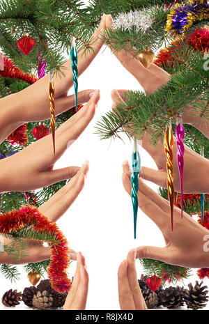 Christmas themed concept of hands making a Christmas tree shape framed with branches and colorful ornaments on white background Stock Photo
