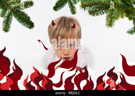 Naughty or good child for Christmas card? PF or letter to Santa-Claus for Christmas. Little child boy appearing as an adorable angelic devil Stock Photo