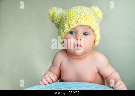 Portrait of a cute newborn baby girl in yellow knitted hat posing on big ball Stock Photo